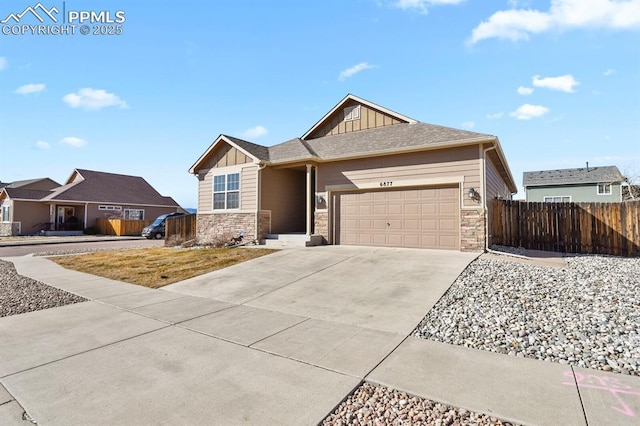 craftsman-style home with fence, an attached garage, concrete driveway, stone siding, and board and batten siding