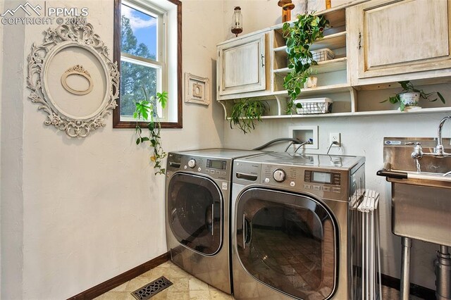 clothes washing area featuring visible vents, baseboards, cabinet space, and washer and dryer