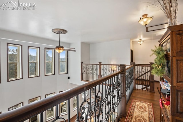 hall with dark wood finished floors and an upstairs landing