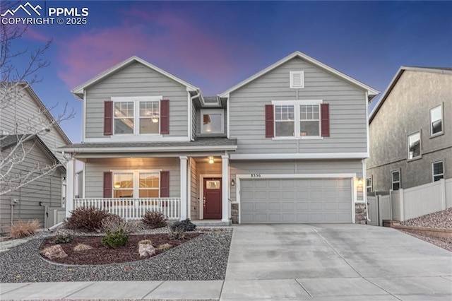 traditional home with a garage, covered porch, fence, and concrete driveway