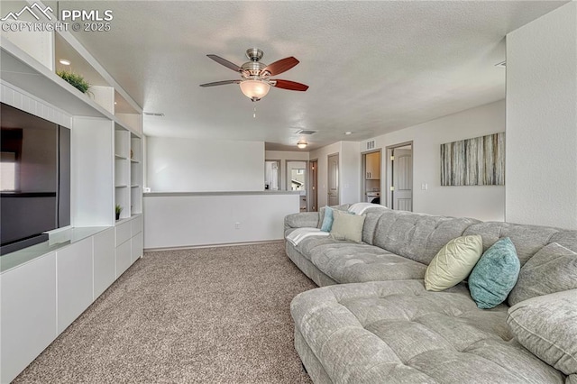 carpeted living area with visible vents, ceiling fan, and a textured ceiling