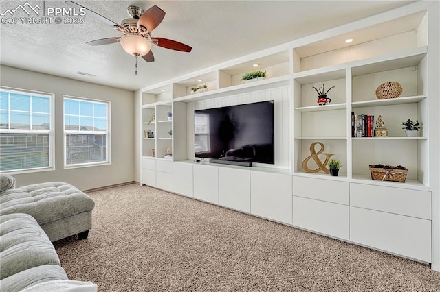 carpeted living area with a textured ceiling, a ceiling fan, visible vents, and built in features