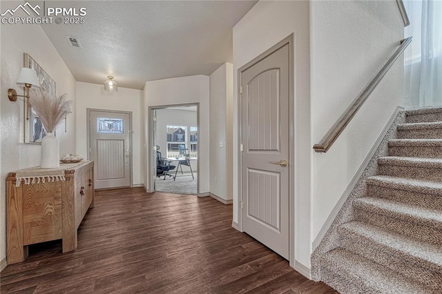 foyer entrance with baseboards, visible vents, dark wood-style floors, stairway, and a textured ceiling