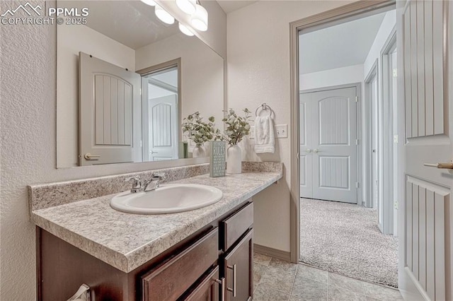 bathroom with a textured wall, vanity, and baseboards