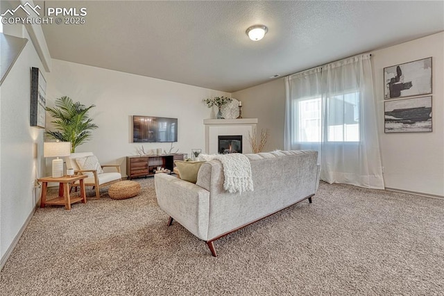 living area with a textured ceiling, baseboards, a glass covered fireplace, and light colored carpet