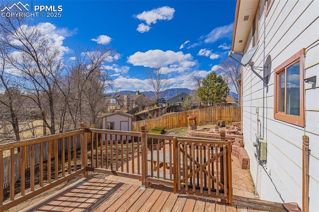 deck featuring a storage shed, fence, and an outdoor structure