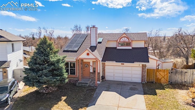 view of front facade featuring a chimney, solar panels, fence, a garage, and driveway