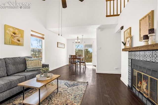 living area with a high ceiling, wood-type flooring, baseboards, and a tiled fireplace