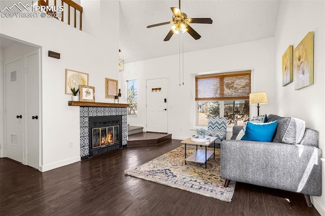 living area with a fireplace, ceiling fan, wood finished floors, high vaulted ceiling, and baseboards