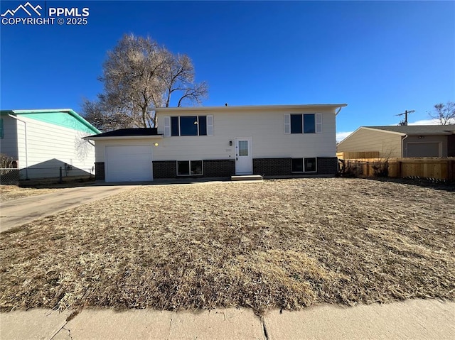 view of front of property with a garage, brick siding, fence, and driveway