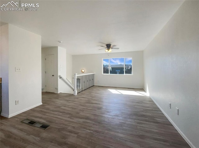 spare room featuring baseboards, visible vents, dark wood finished floors, and a ceiling fan