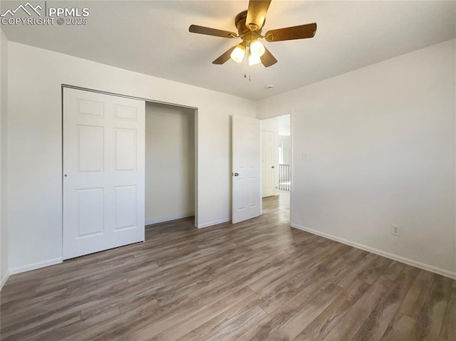 unfurnished bedroom with a closet, wood finished floors, a ceiling fan, and baseboards