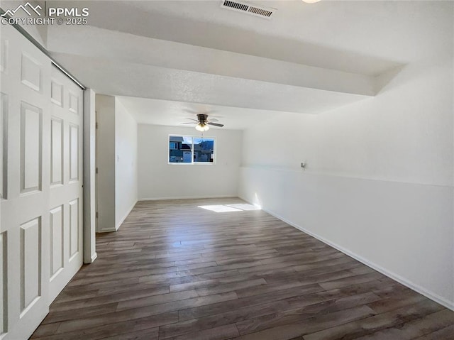 spare room featuring dark wood-type flooring, visible vents, ceiling fan, and baseboards