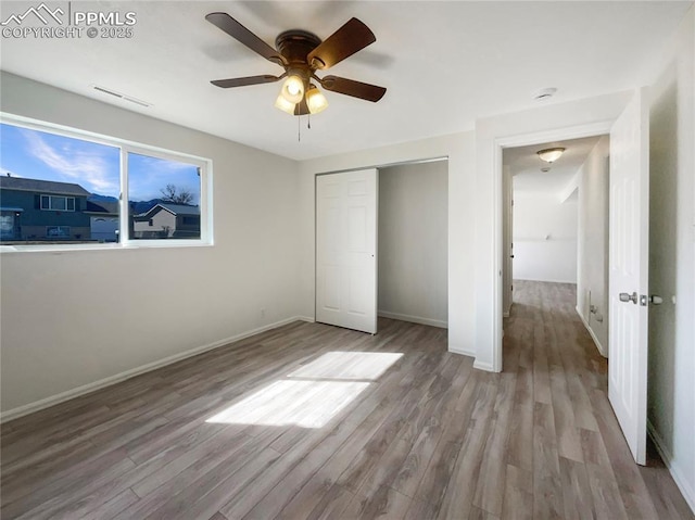 unfurnished bedroom with visible vents, a closet, baseboards, and wood finished floors