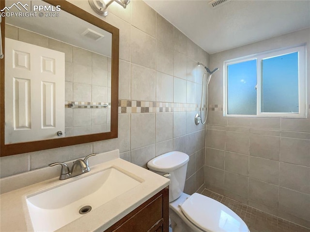 bathroom featuring tile walls, tiled shower, toilet, vanity, and backsplash