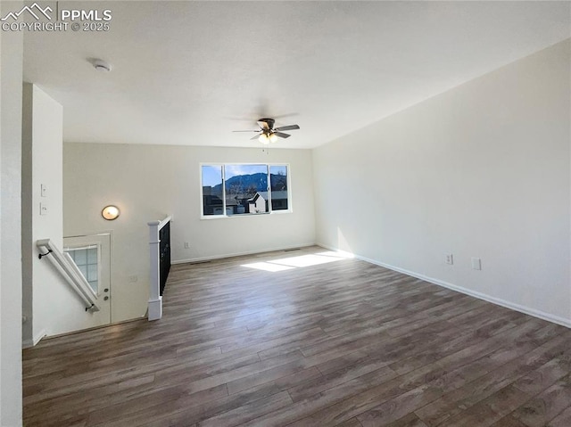 empty room featuring a ceiling fan, dark wood finished floors, and baseboards