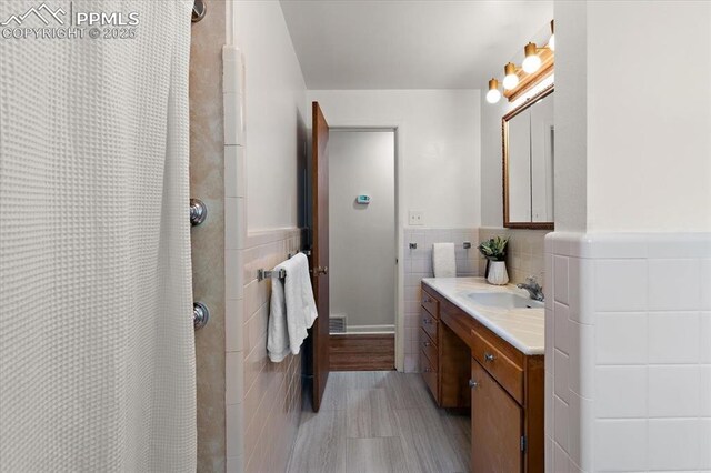 1328 Swope Ave, Colorado Springs, CO 80909 - full bathroom with tile walls, vanity, a shower with curtain, and a wainscoted wall