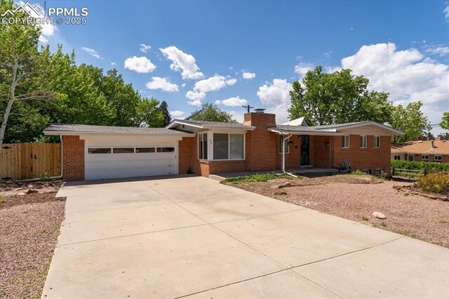 1328 Swope Ave, Colorado Springs, CO 80909 - single story home with an attached garage, driveway, brick siding, and a chimney