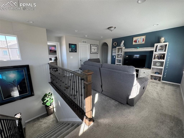 carpeted living area featuring arched walkways, visible vents, a textured ceiling, and baseboards