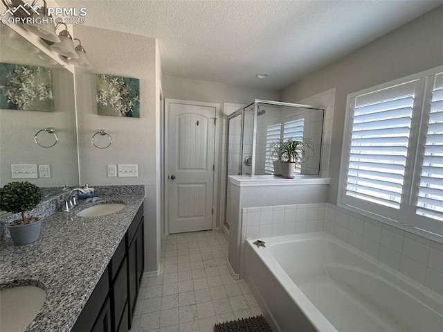 bathroom featuring double vanity, a sink, a textured ceiling, a shower stall, and a bath