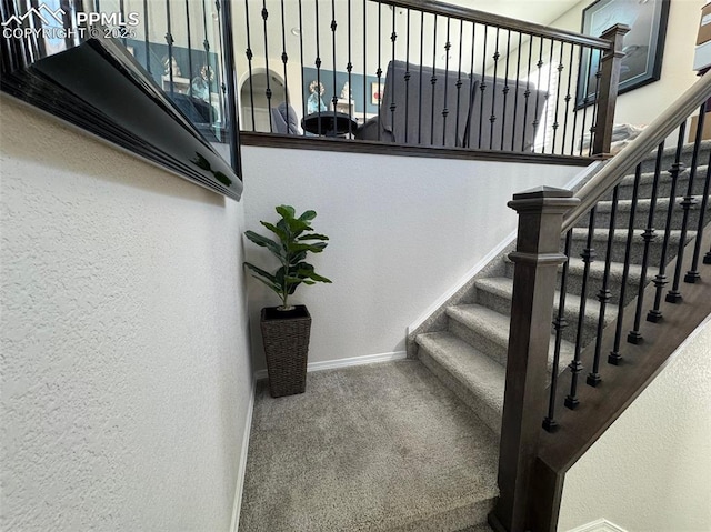 stairway with baseboards, carpet flooring, and a textured wall