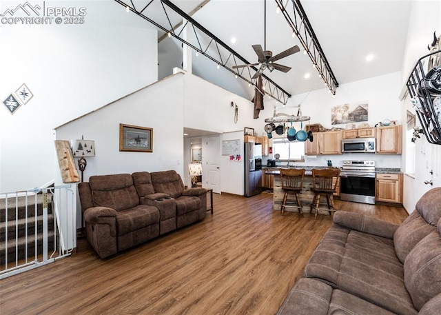 living room with dark wood-style floors, a high ceiling, and a ceiling fan