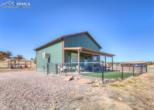 view of front facade featuring fence, board and batten siding, and a wall mounted air conditioner