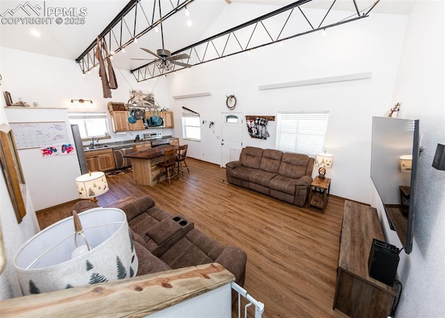 living area with dark wood-style floors, ceiling fan, and a high ceiling