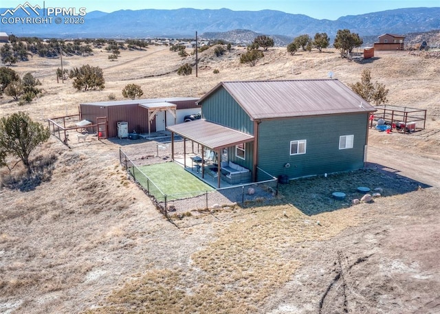 rear view of property with an outbuilding, a desert view, a mountain view, and fence