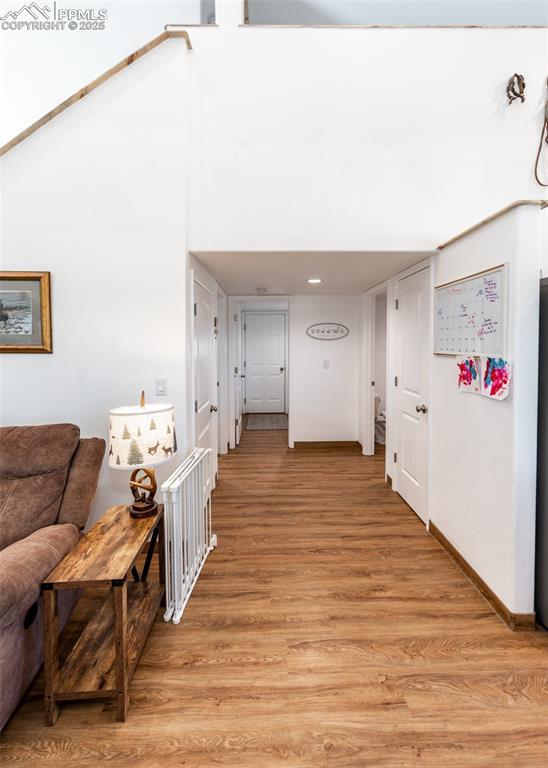 hallway with light wood-type flooring and a high ceiling