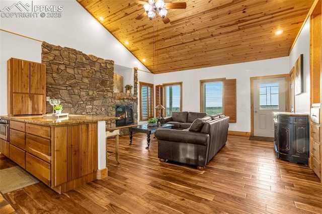 living room with a stone fireplace, wood finished floors, high vaulted ceiling, wooden ceiling, and baseboards