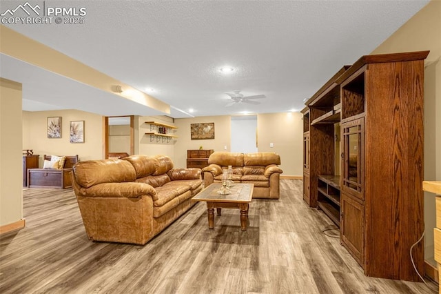 living room with baseboards, light wood-style flooring, and a textured ceiling