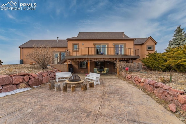 rear view of house with a deck, an outdoor fire pit, a patio area, and stucco siding