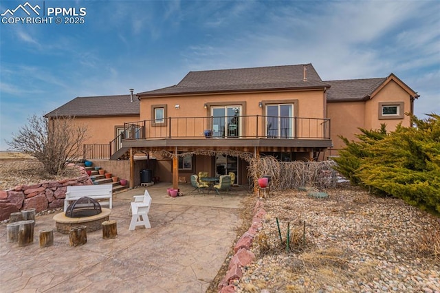 back of house featuring stucco siding, an outdoor fire pit, stairway, and a patio