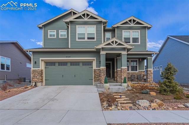 craftsman inspired home featuring a garage, driveway, stone siding, and central air condition unit