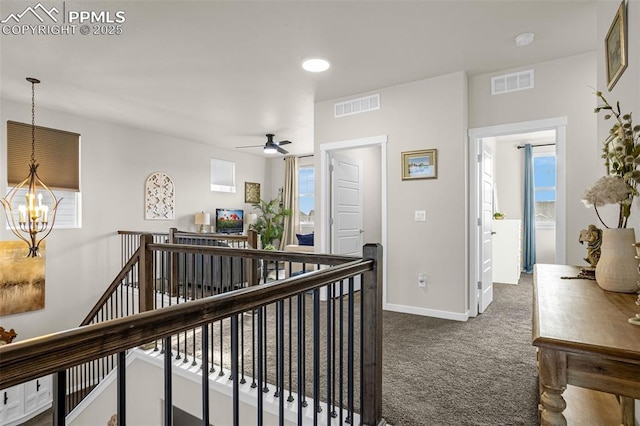 hall with carpet, visible vents, an upstairs landing, and an inviting chandelier