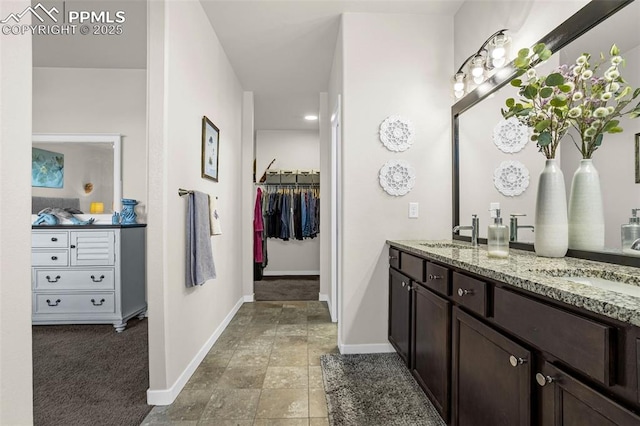 full bathroom with double vanity, a sink, and baseboards