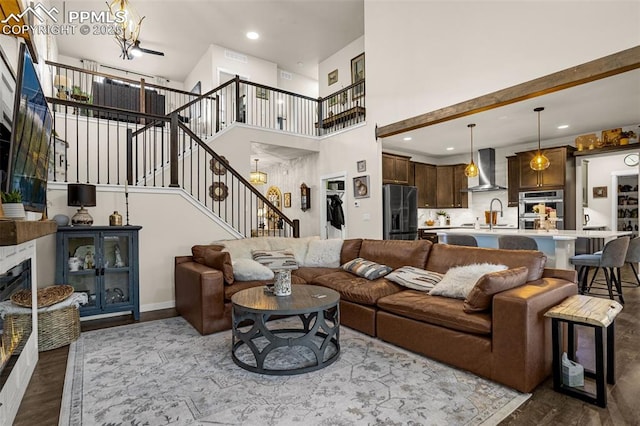 living room featuring a fireplace, dark wood finished floors, recessed lighting, stairway, and an inviting chandelier