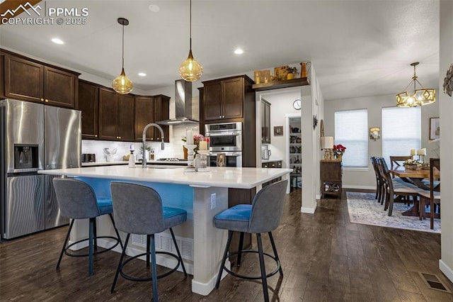 kitchen with stainless steel appliances, visible vents, dark wood-type flooring, dark brown cabinetry, and wall chimney exhaust hood