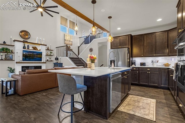 kitchen with stainless steel appliances, a glass covered fireplace, dark wood finished floors, and dark brown cabinets