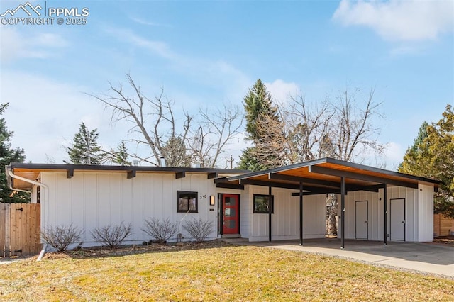 view of front facade featuring a front yard, fence, concrete driveway, a carport, and board and batten siding