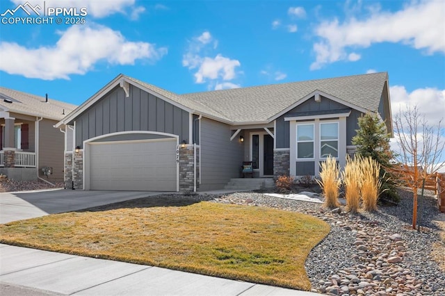 view of front of house with board and batten siding, a garage, stone siding, driveway, and a front lawn