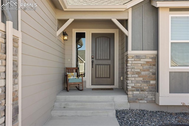 entrance to property with stone siding and roof with shingles