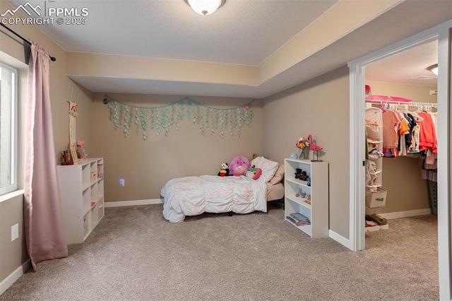 carpeted bedroom featuring a closet, baseboards, a walk in closet, and a textured ceiling