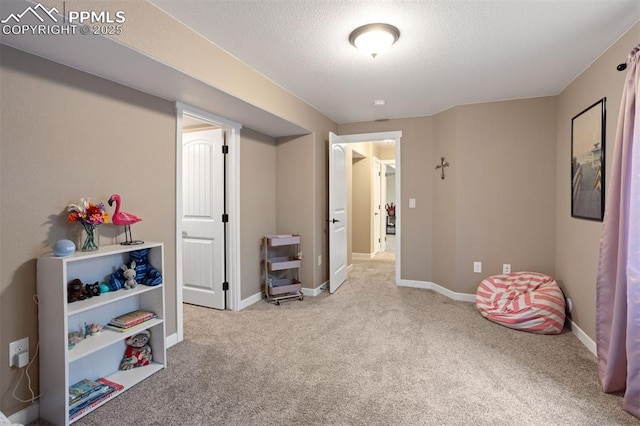 playroom featuring a textured ceiling, baseboards, and carpet flooring