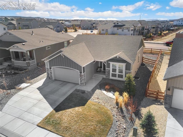 view of front facade featuring board and batten siding, a residential view, stone siding, and fence