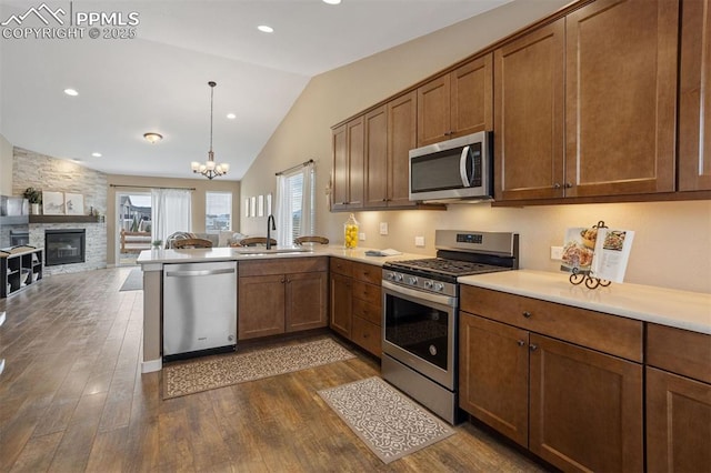 kitchen featuring appliances with stainless steel finishes, open floor plan, dark wood-style flooring, vaulted ceiling, and a sink