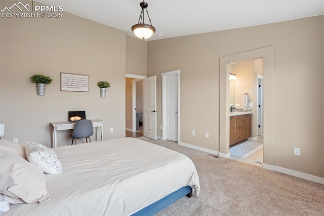 bedroom with lofted ceiling, light colored carpet, ensuite bath, and baseboards