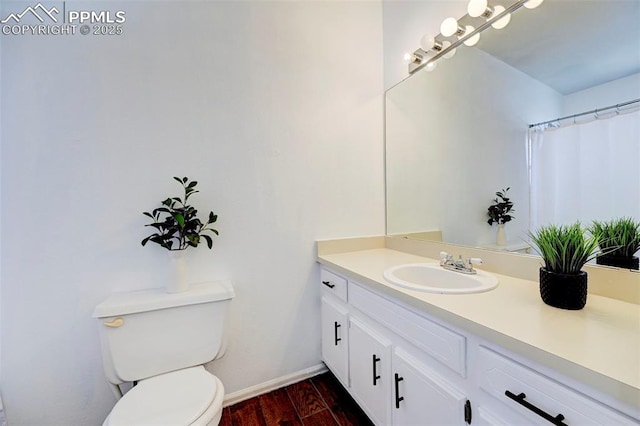 bathroom with vanity, toilet, wood finished floors, and baseboards