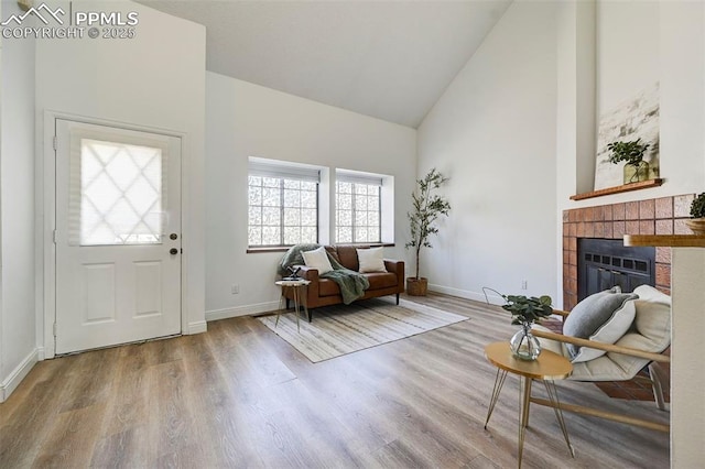 entrance foyer featuring baseboards, high vaulted ceiling, wood finished floors, and a fireplace